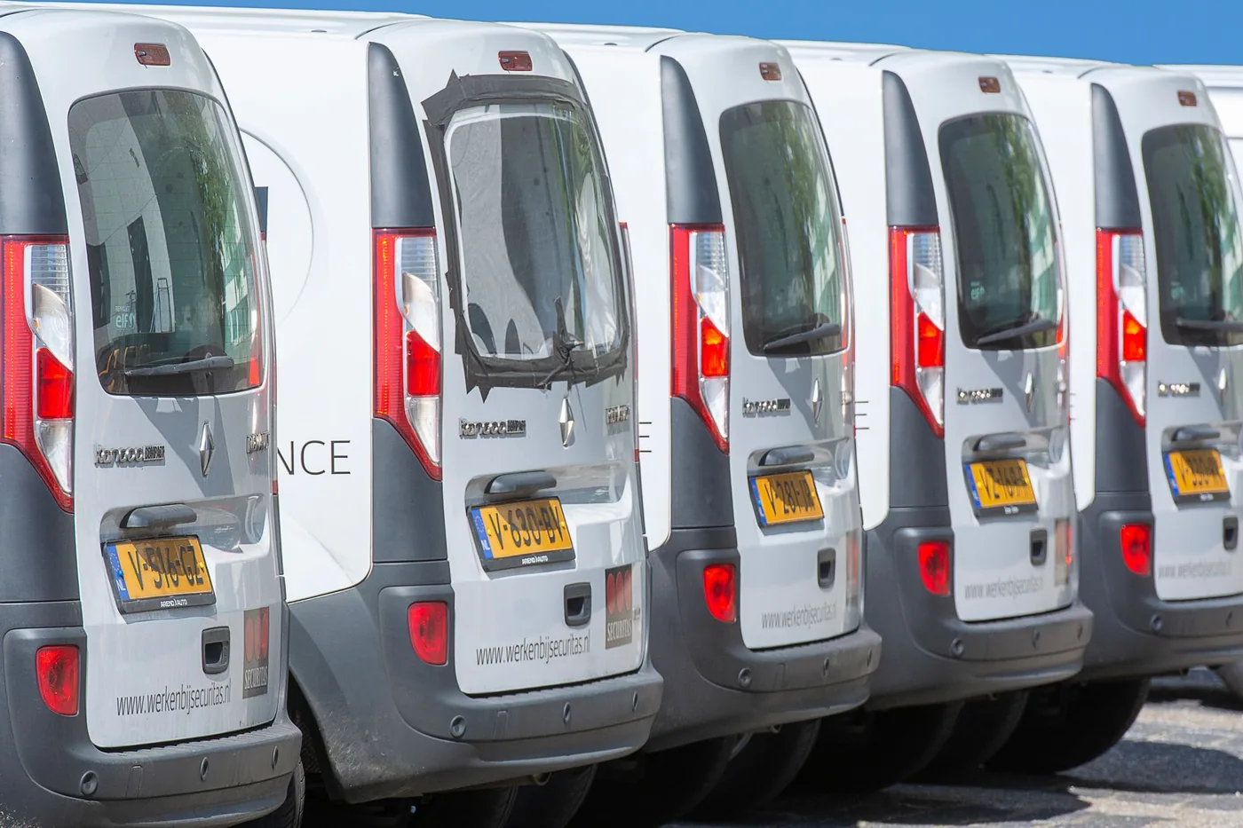 Reihe weisser Lieferwagen auf einem Parkplatz, illustratives Stockfoto